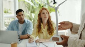 someone showing a wind turbine model to two people sitting at a desk. Environmental Law Practice